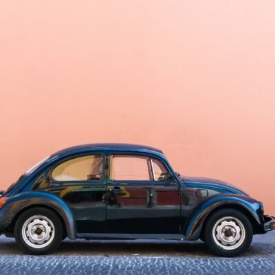 black Volkswagen Beetle beside beige wall